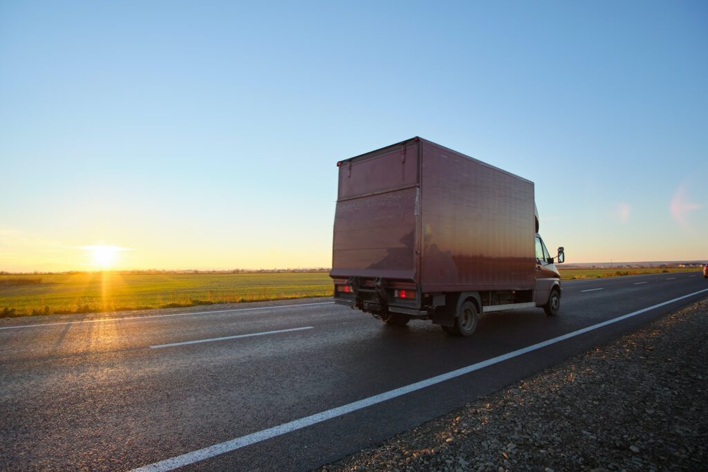 Cargo truck driving on highway hauling goods in evening. Delivery transportation and logistics